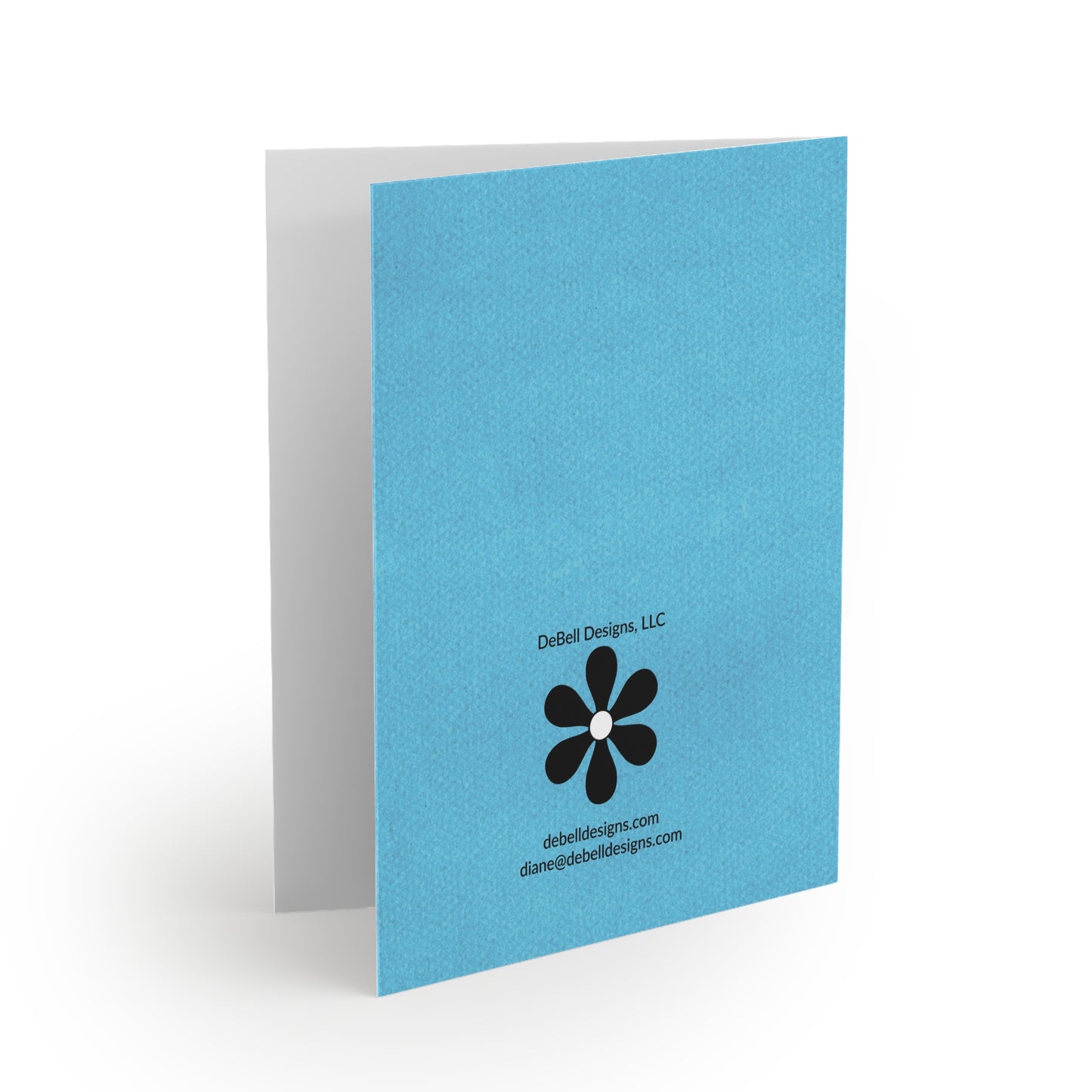 “Open birthday greeting card with a bright blue back cover featuring black text for DeBell Designs, a black flower icon, and website/email.”