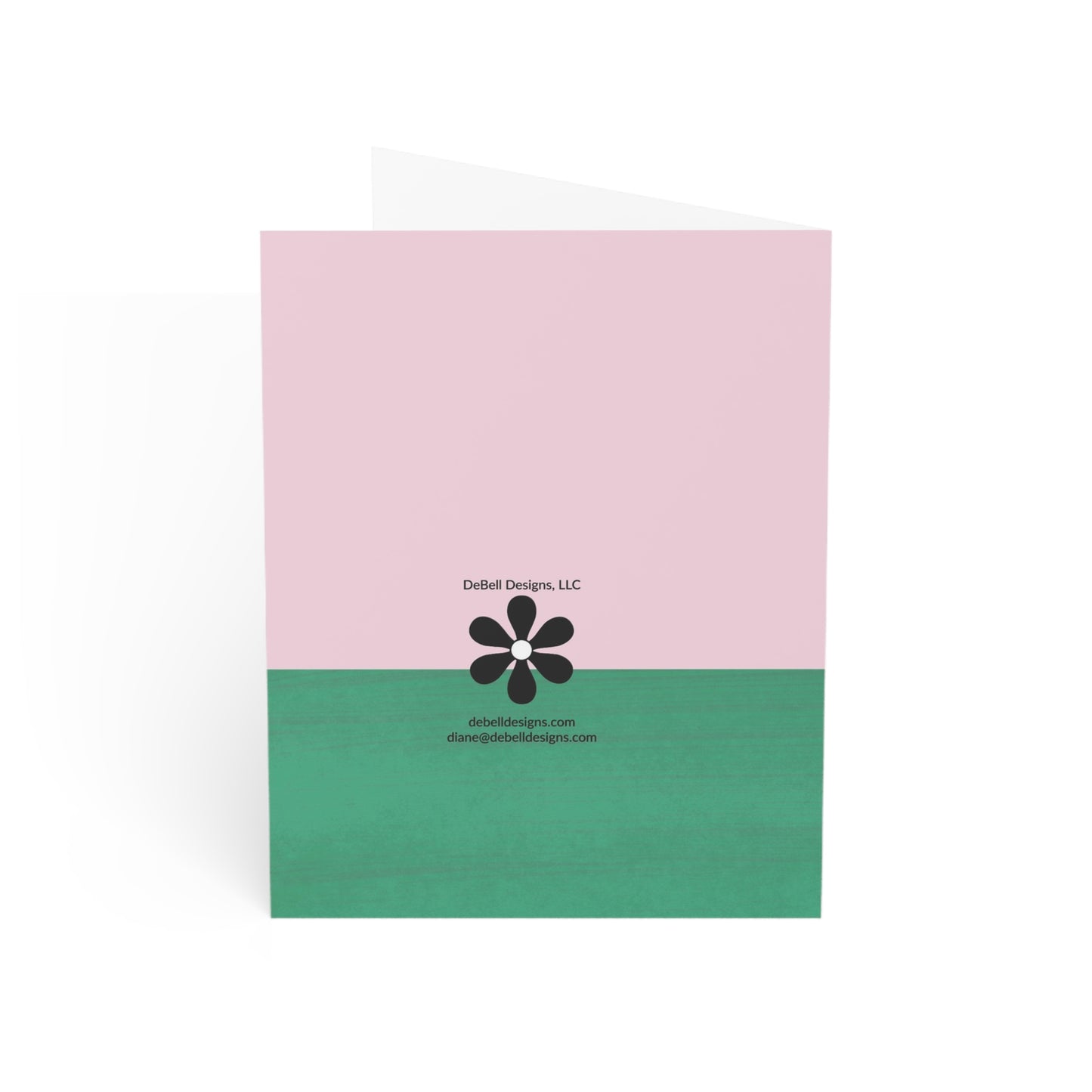 A vertically-oriented folded card, solid pink upper half, and green lower half. A black flower with a white center and the text "DeBell Designs, LLC debelldesigns.com diane@debelldesigns.com" is centered in the card's middle.