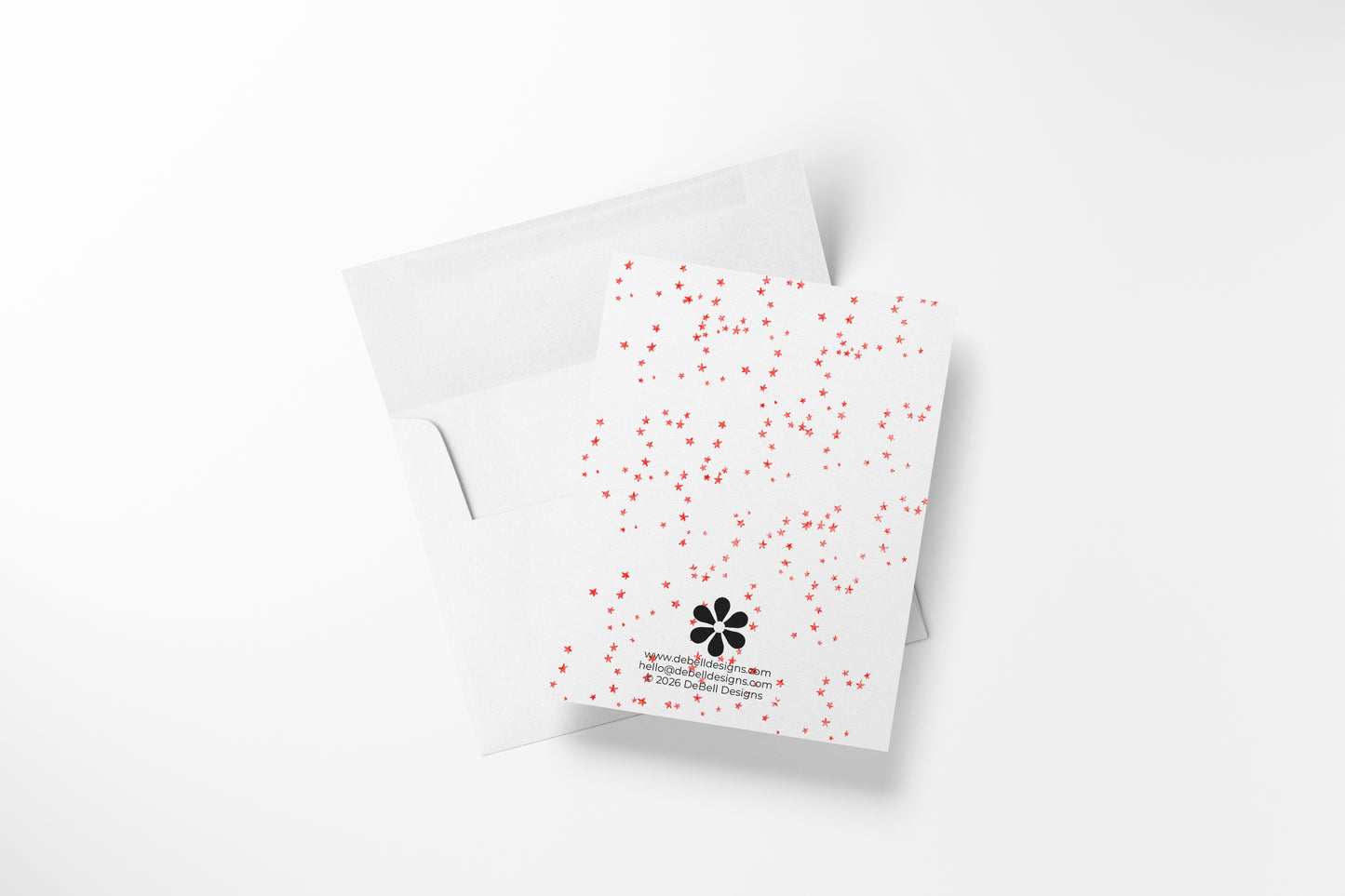 Rear view of a white greeting card with a scattered red star pattern and an open white envelope on a white surface.