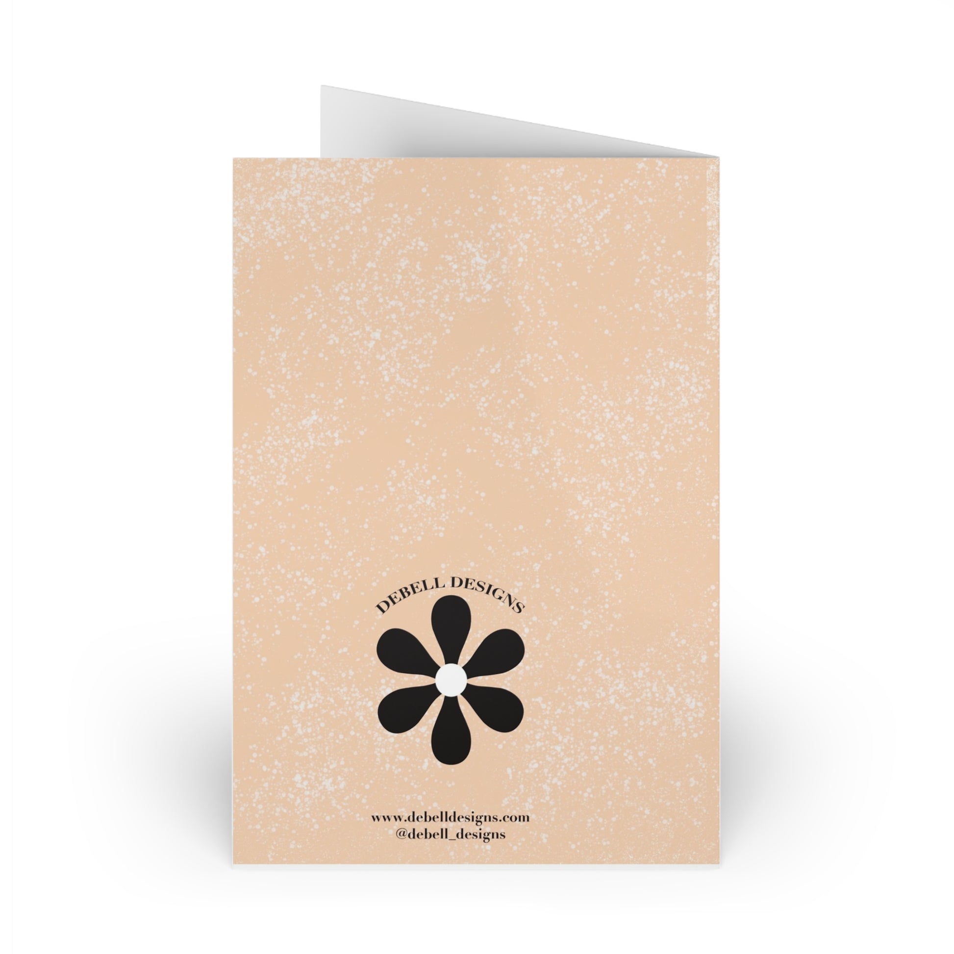 {"altText": "Open greeting card standing vertically, back view. Beige with brown speckles, a black flower logo, and "DEBELL DESIGNS" text."}