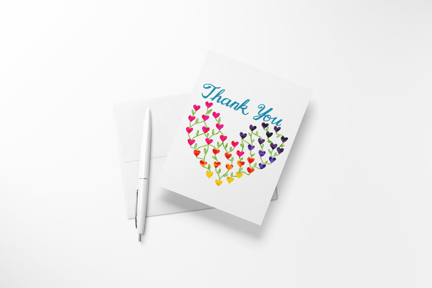 Rainbow hearts thank you card by DeBell Designs styled with a white pen and white envelope.