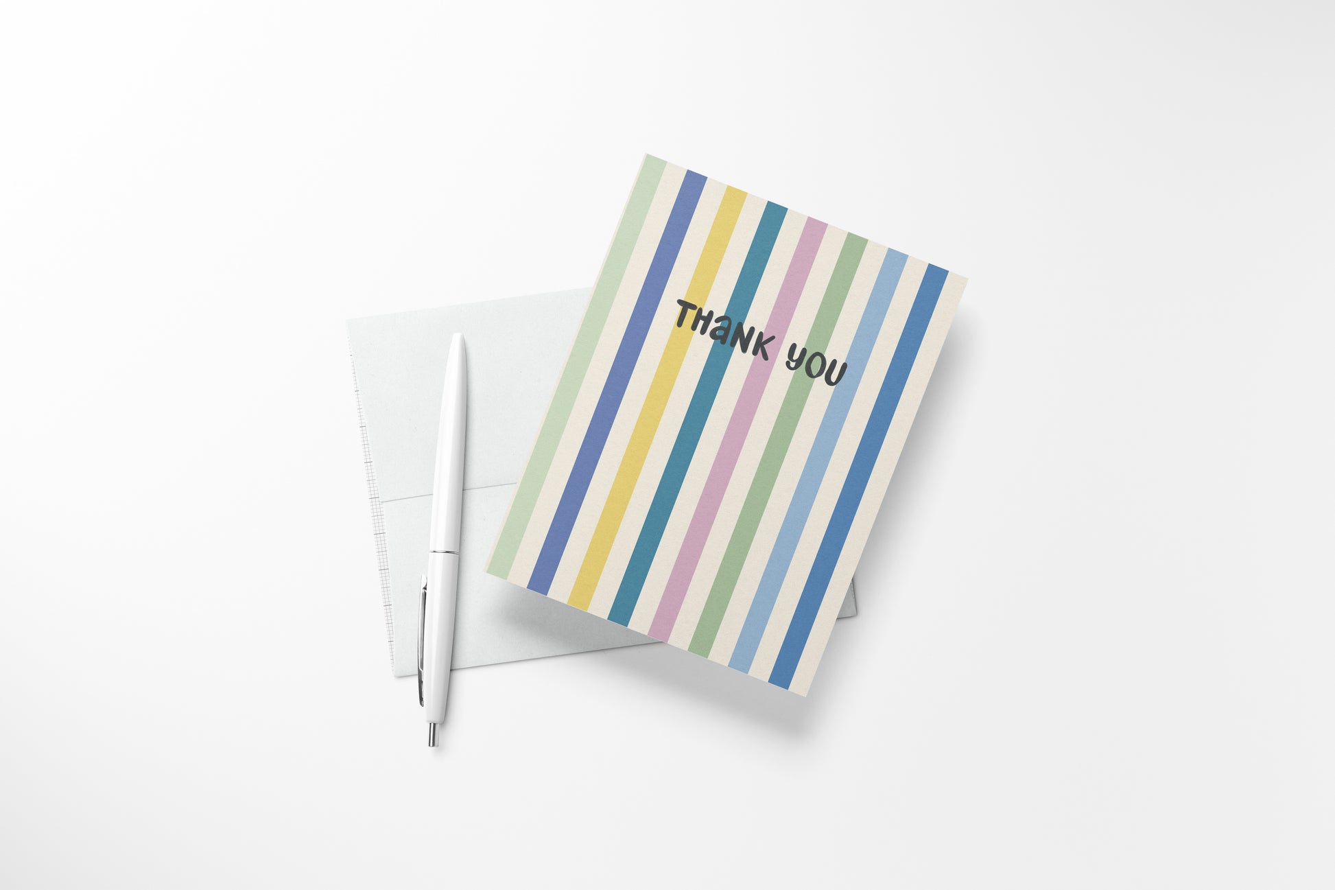 An A2  thank-you card with vertical pastel stripes in blue, green, yellow, pink, and purple, placed on top of a white envelope with a white pen beside it on a light background.