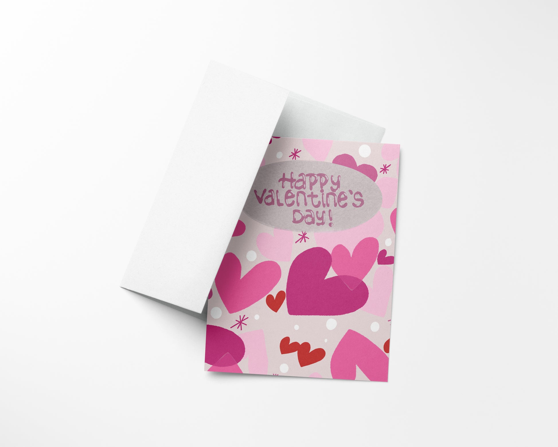 A Valentine's Day card with pink and red hearts, and dotted patterns, partially visible in an open white envelope with text that reads, "HAPPY VALENTINE'S DAY!"
