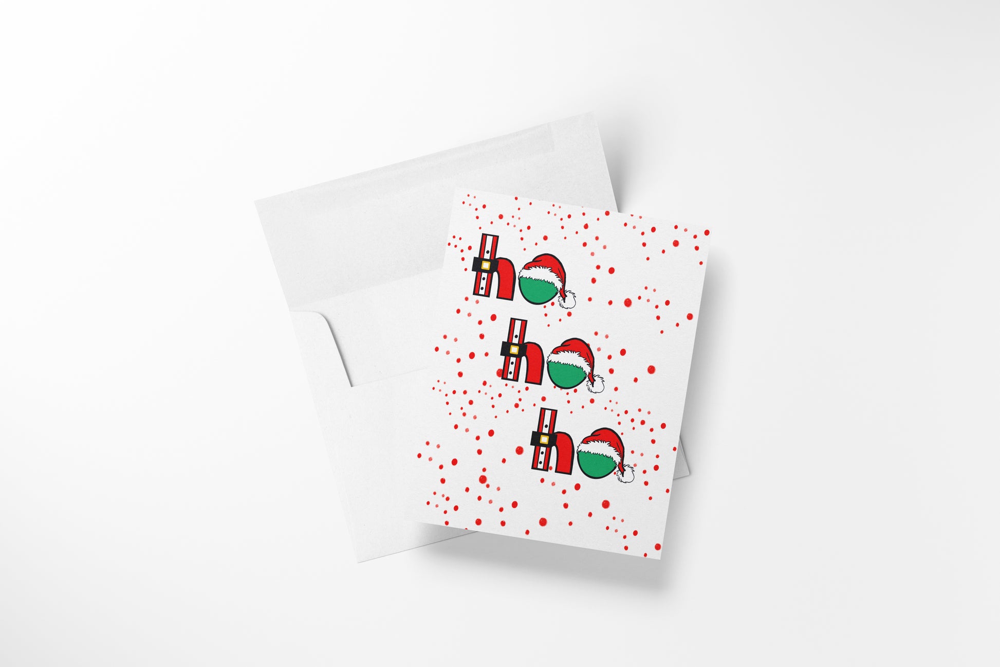 {"altText": "White greeting card with red polka dots and "ho ho ho" in red and green with Santa hats and belts; white envelope below."}