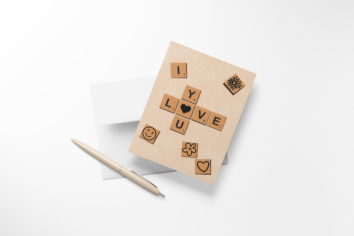 I love you" Scrabble tile greeting card, with heart, flower, and smiley face illustrations with cream pen