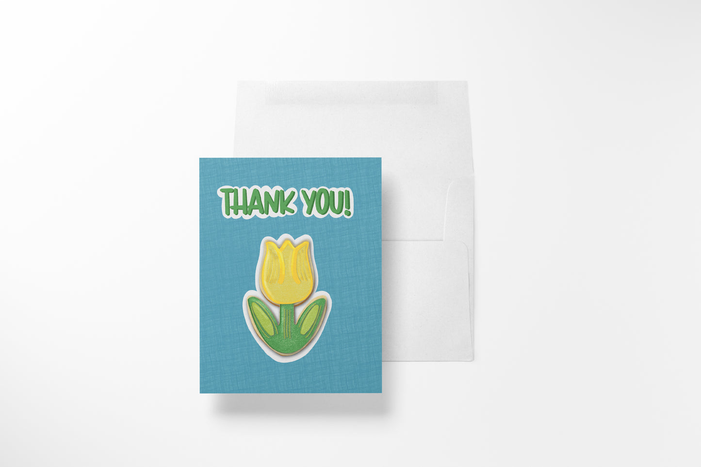 Hand-illustrated Thank You Tulip Cookie greeting card with a yellow tulip sugar cookie on a teal linen background, shown with its white envelope.
