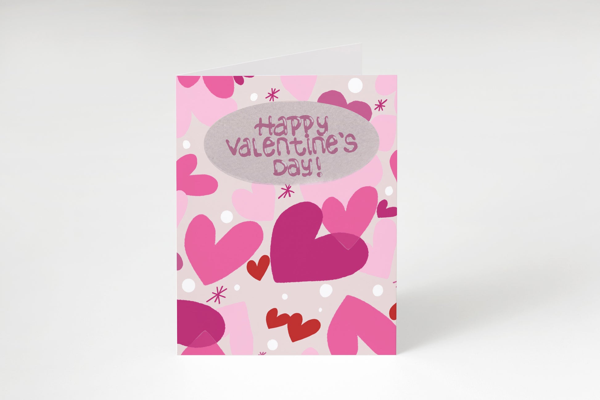 A greeting card with pink hearts and dots on a light pink background, reading "Happy Valentine's Day!" in pink.